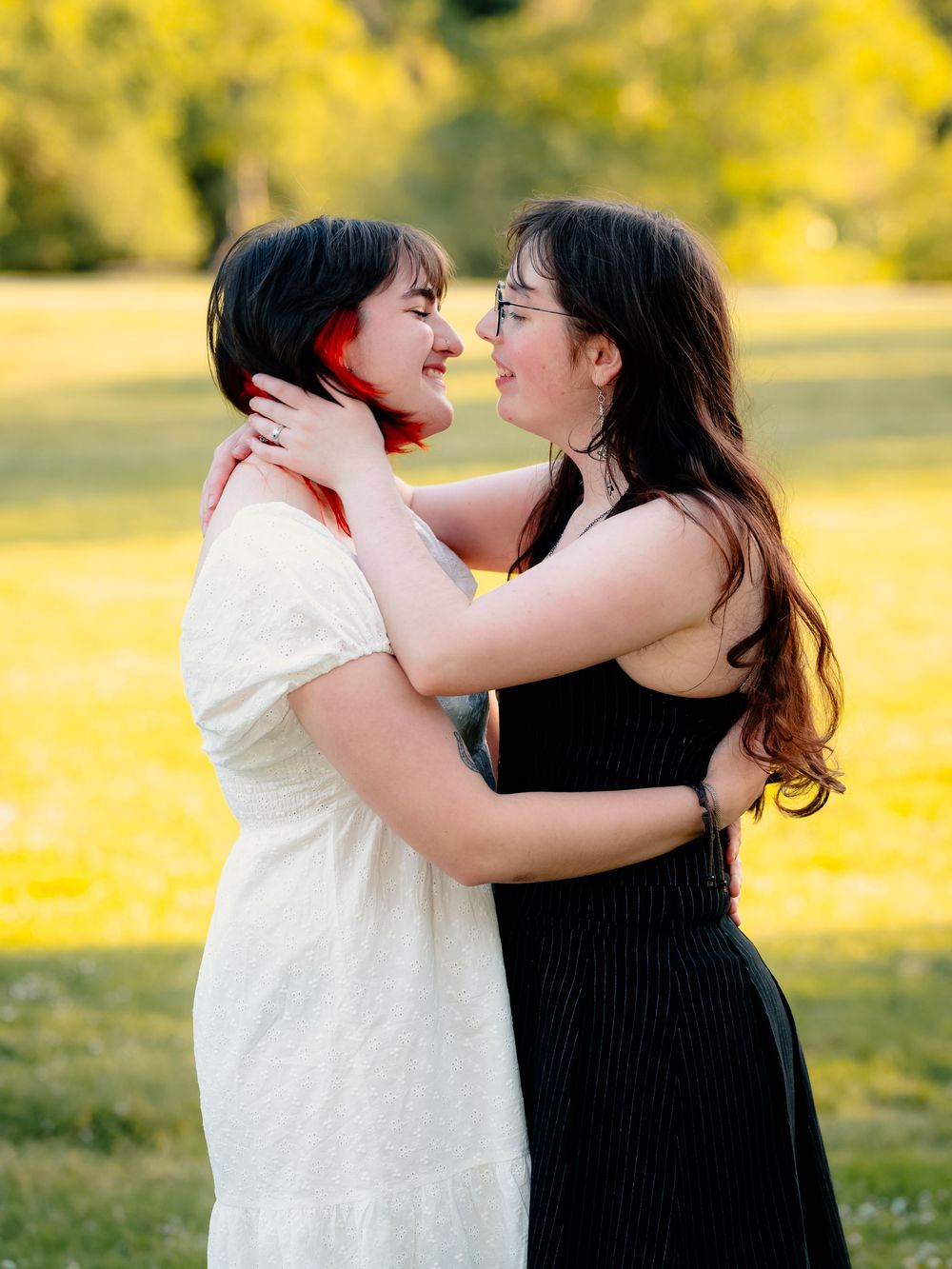 Two people embrace lovingly in a sunlit field with golden autumn foliage in the background.