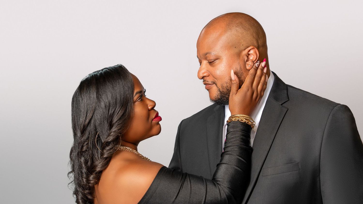 Romantic couple photoshoot with elegant formal attire against a light background.