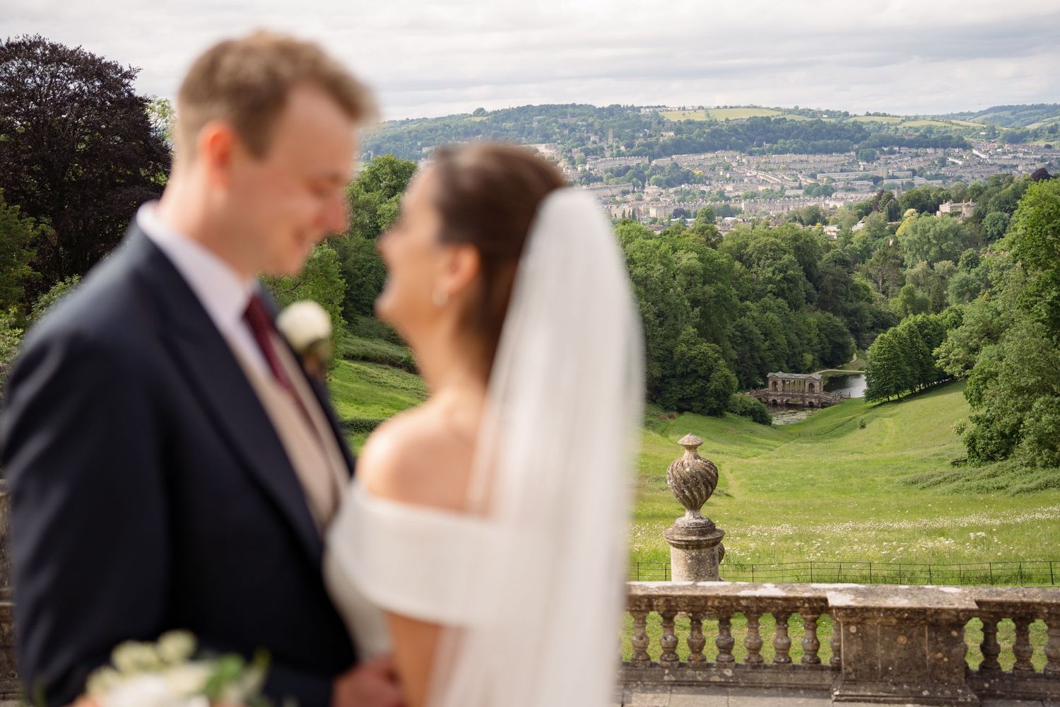 Bride and groom share a romantic moment at an elegant estate wedding venue with scenic countryside views in the background.