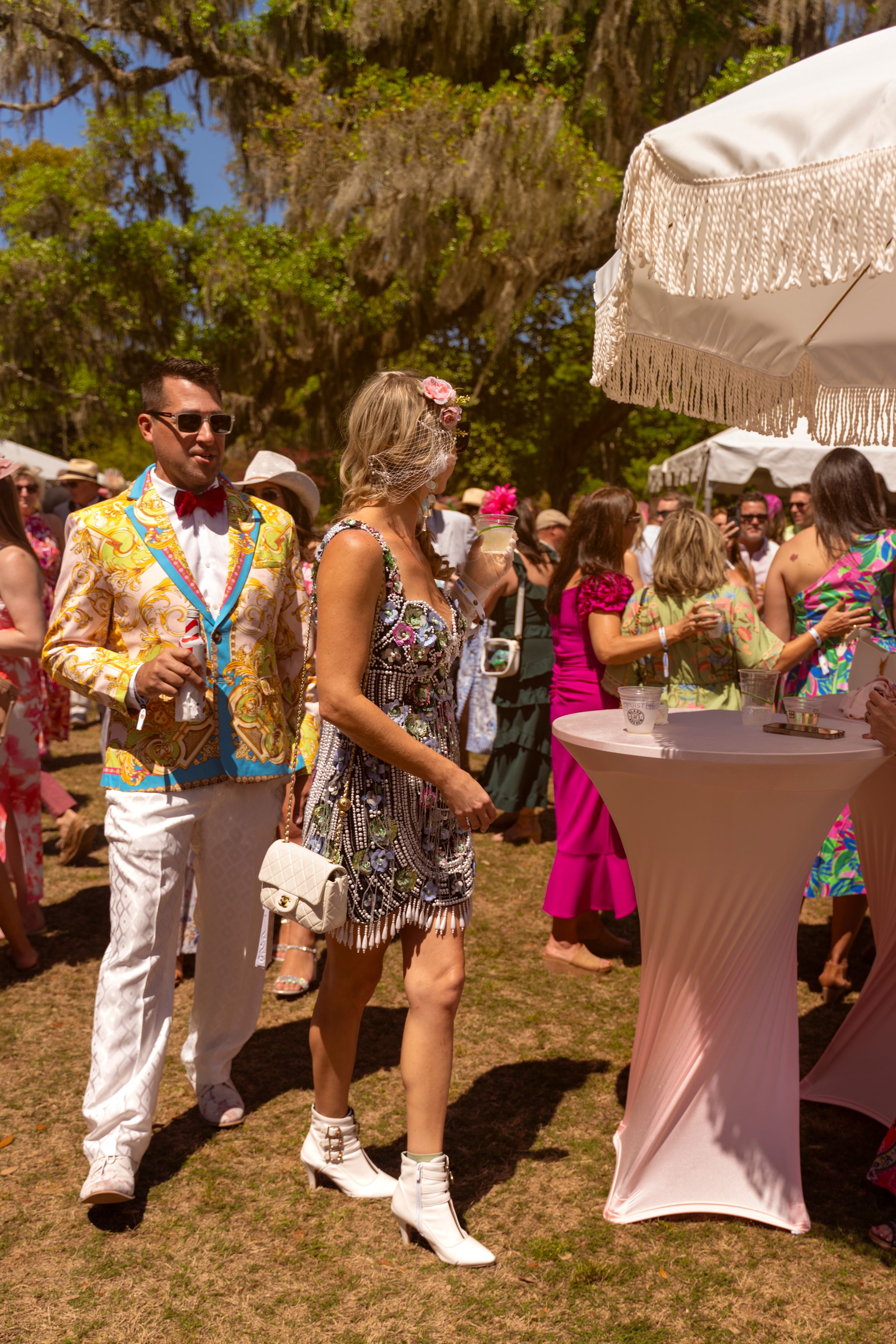 Elegantly dressed couple in colorful attire socializing at an outdoor garden party event.