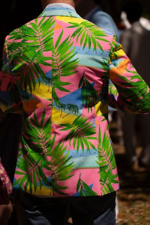 Colorful tropical palm leaf print blazer in pink, green, and blue worn at an outdoor event.