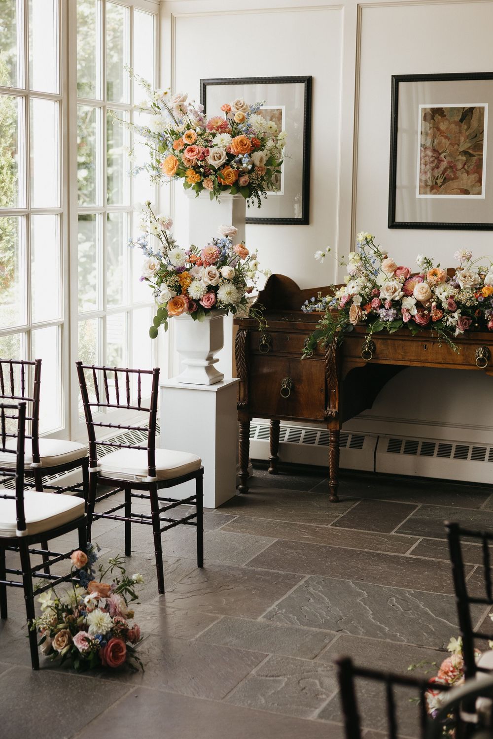 Elegant wedding ceremony backdrop with colourful floral arrangements on antique wooden hutch in the conservatory at Langdon Hall