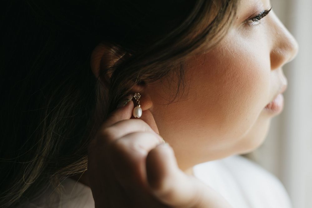 Close-up of a bride wearing a delicate pearl and crystal drop earring on her wedding day.