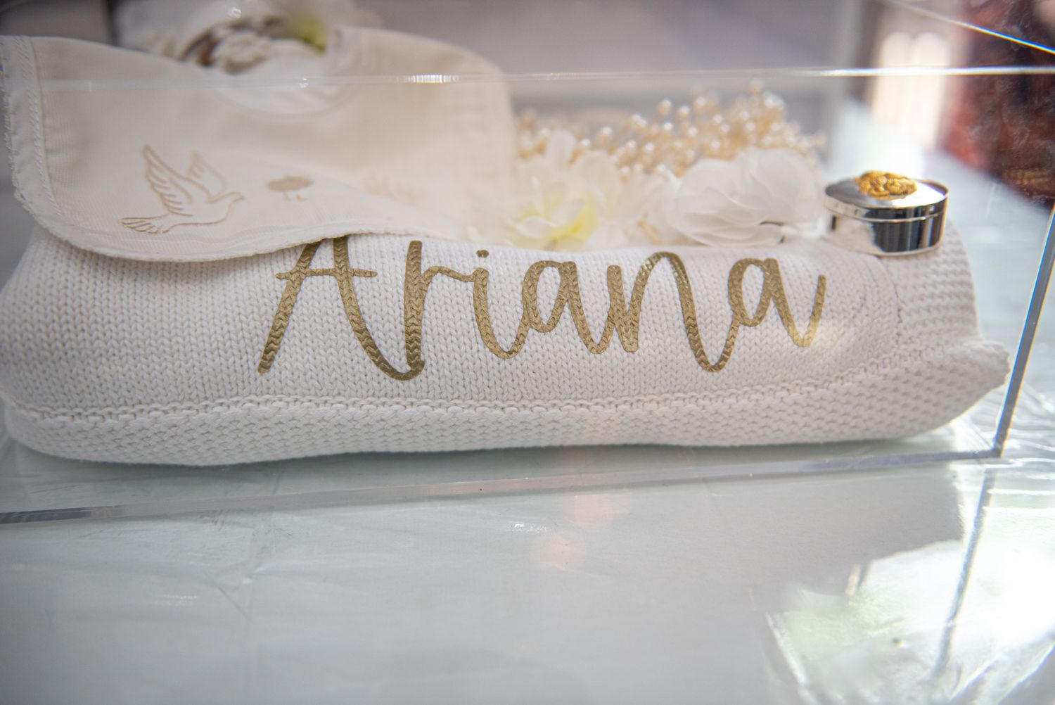 Personalized white clutch bag with gold script name Ariana, decorated with white flowers for a baptism.