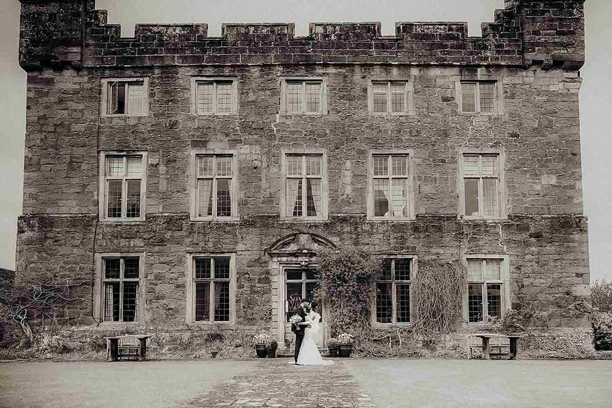 Bride and groom kiss in front of Askham Hall wedding venue near Penrith