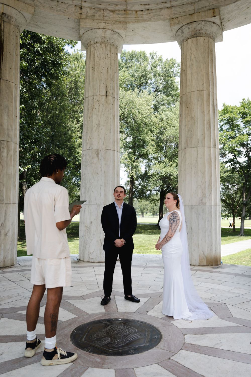 Couple exchanges vows at DC War Memorial colonnade with officiant.