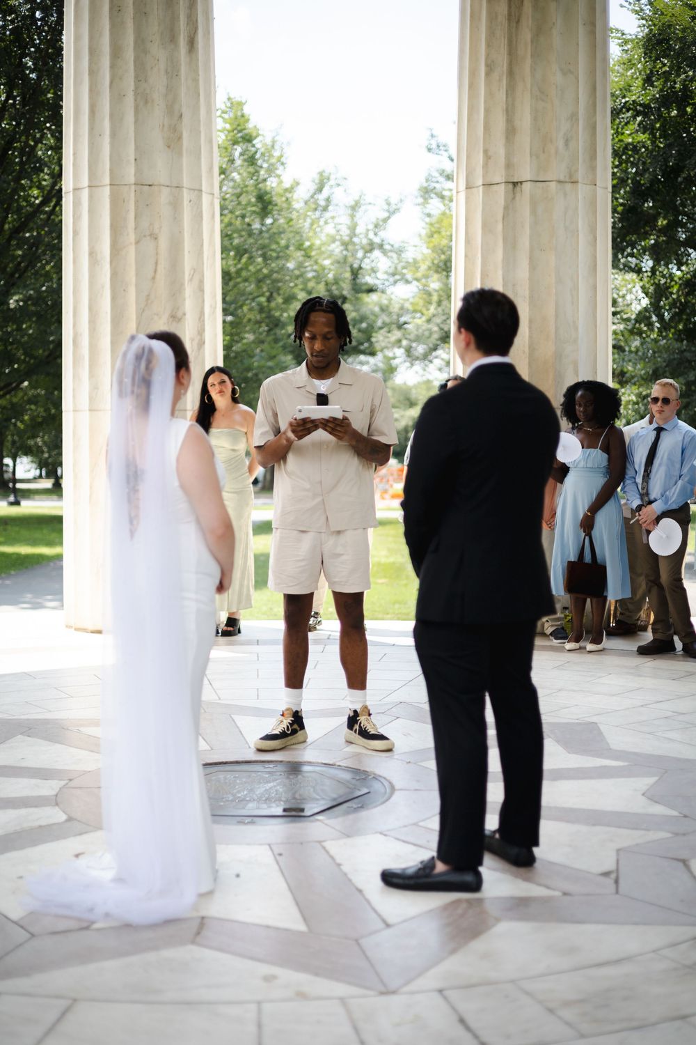 Wedding ceremony at DC memorial with officiant reading vows between bride and groom.