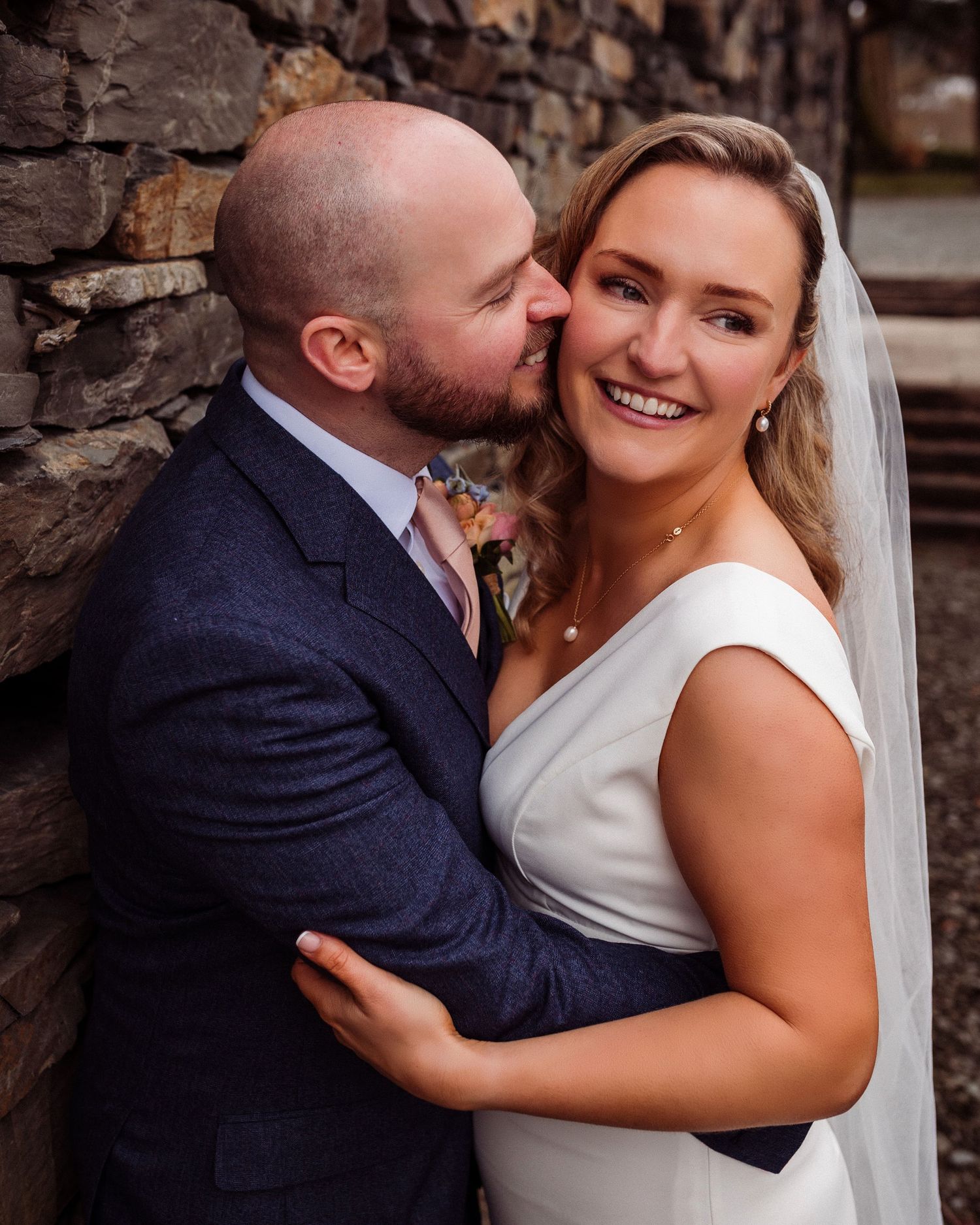 Close portrait of couple together at Storrs Hall - groom kissing bride's cheek
