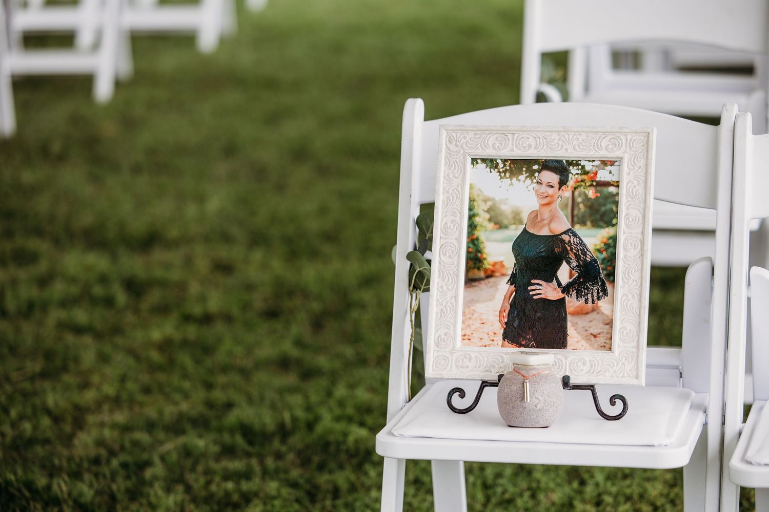Framed photo of a woman in a black dress displayed on a white chair at an outdoor wedding ceremony in Fort Worth.