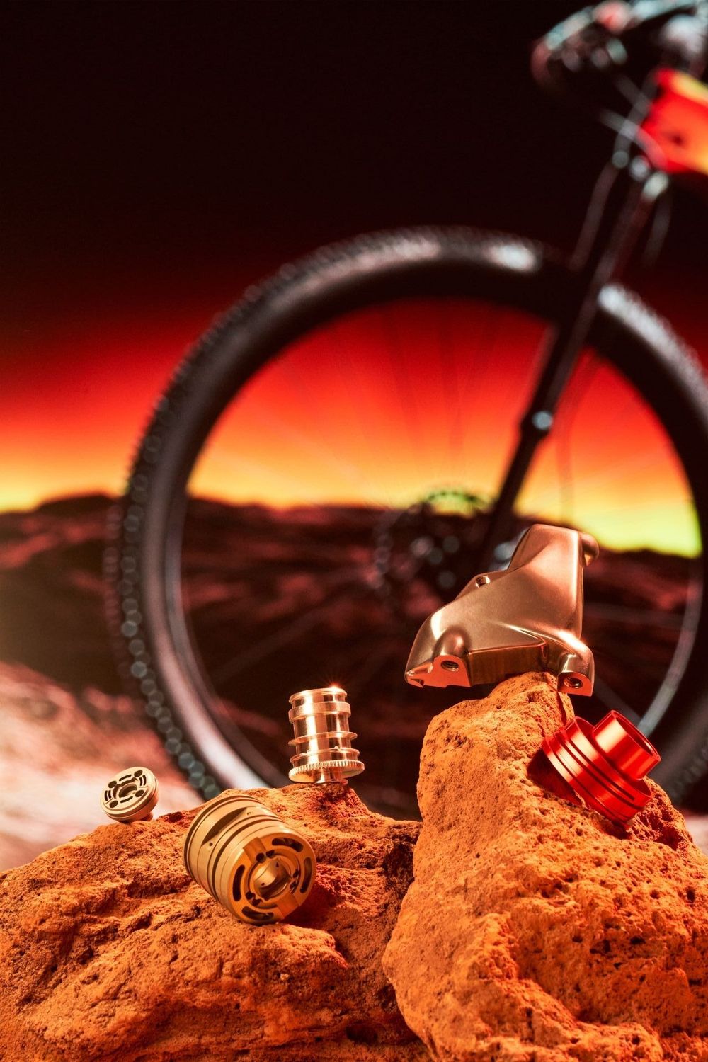 Vaping accessories arranged on red rocks with a mountain bike silhouetted against a sunset backdrop.