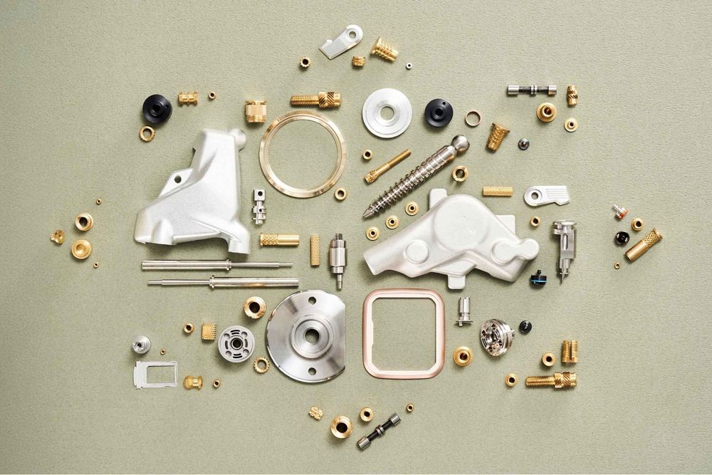 Disassembled mechanical parts and components laid out in organized pattern on light gray surface.