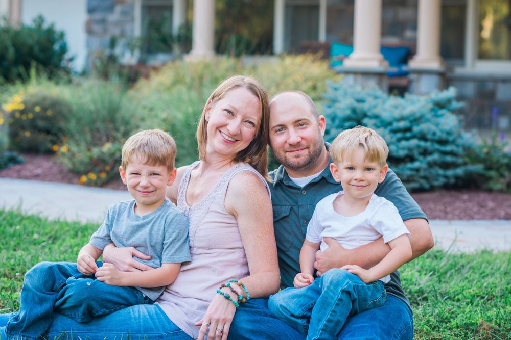 Family relaxing together on steps in a garden setting.