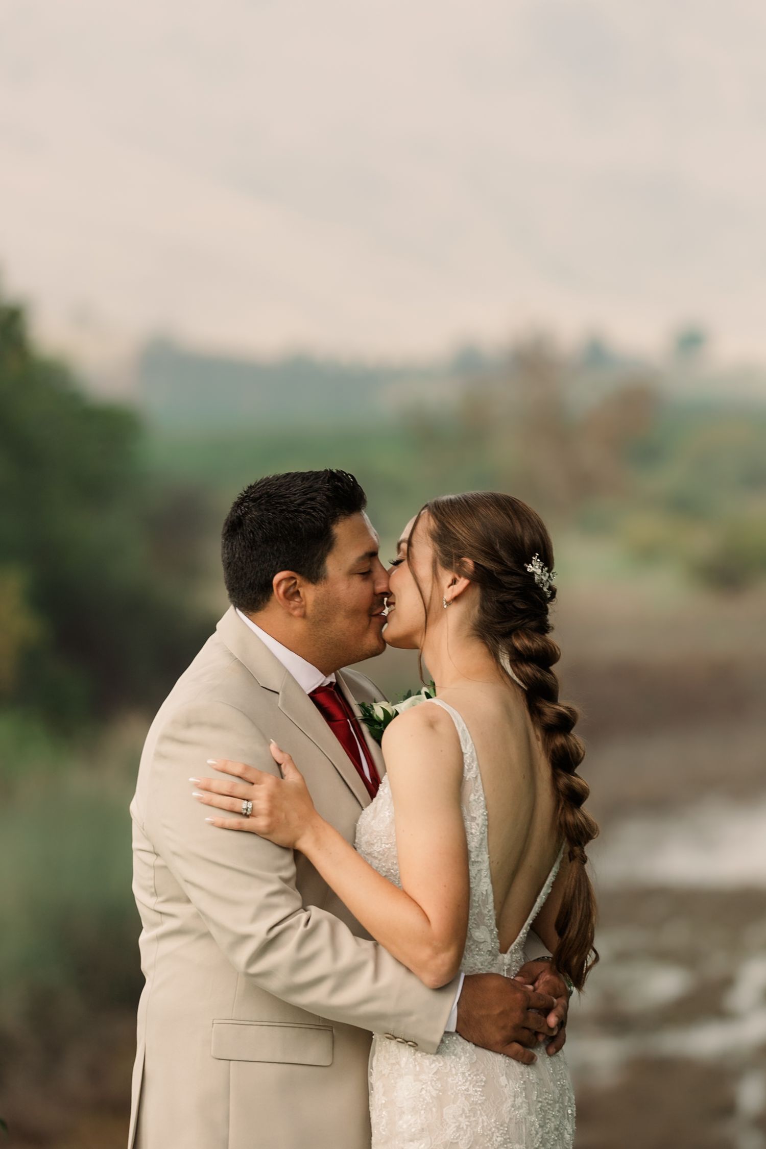 A romantic wedding couple shares intimate kisses in a series of photos against a blurred outdoor landscape background.