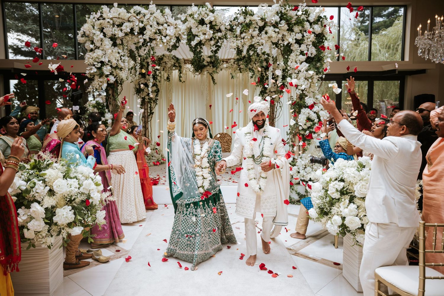 Joyful South Asian wedding at Lucien's Manor in Berlin, NJ, with the couple walking the aisle under a floral mandap and rose petal shower.