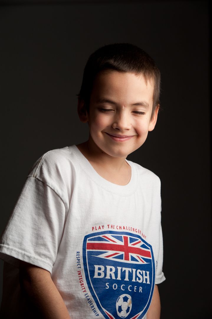 Marshall smiling while looking down towards floor against black paper background.