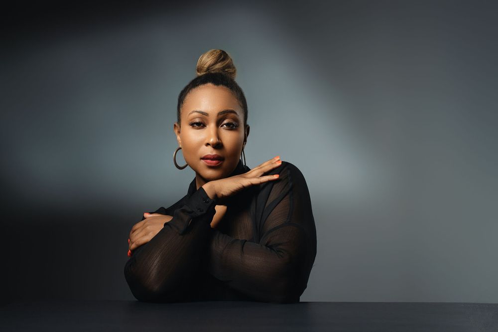 Professional studio portrait of someone in a black sheer top against a dark gray background.