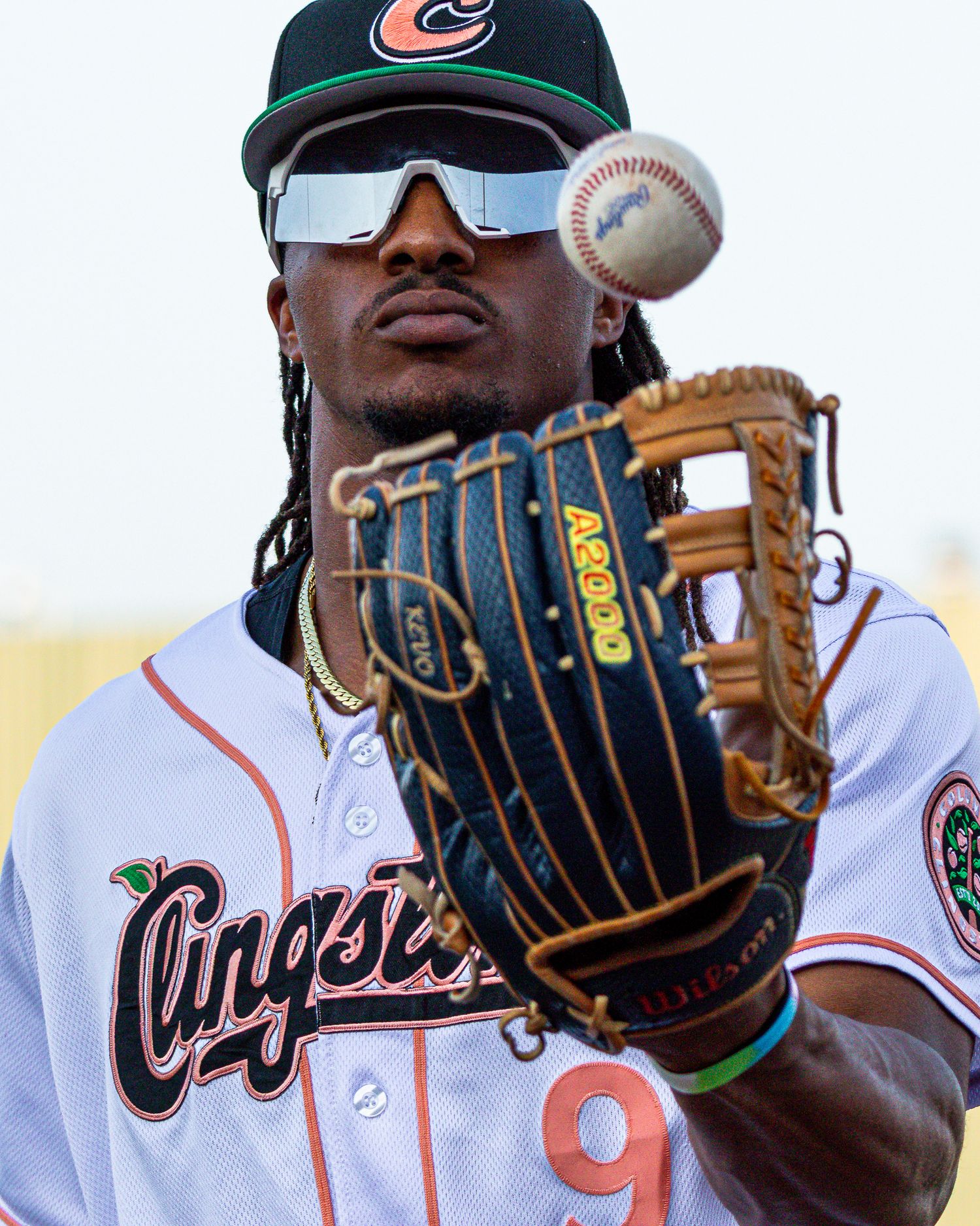 Baseball players in uniforms hold up their gloves while posing with a baseball at a team photo session.