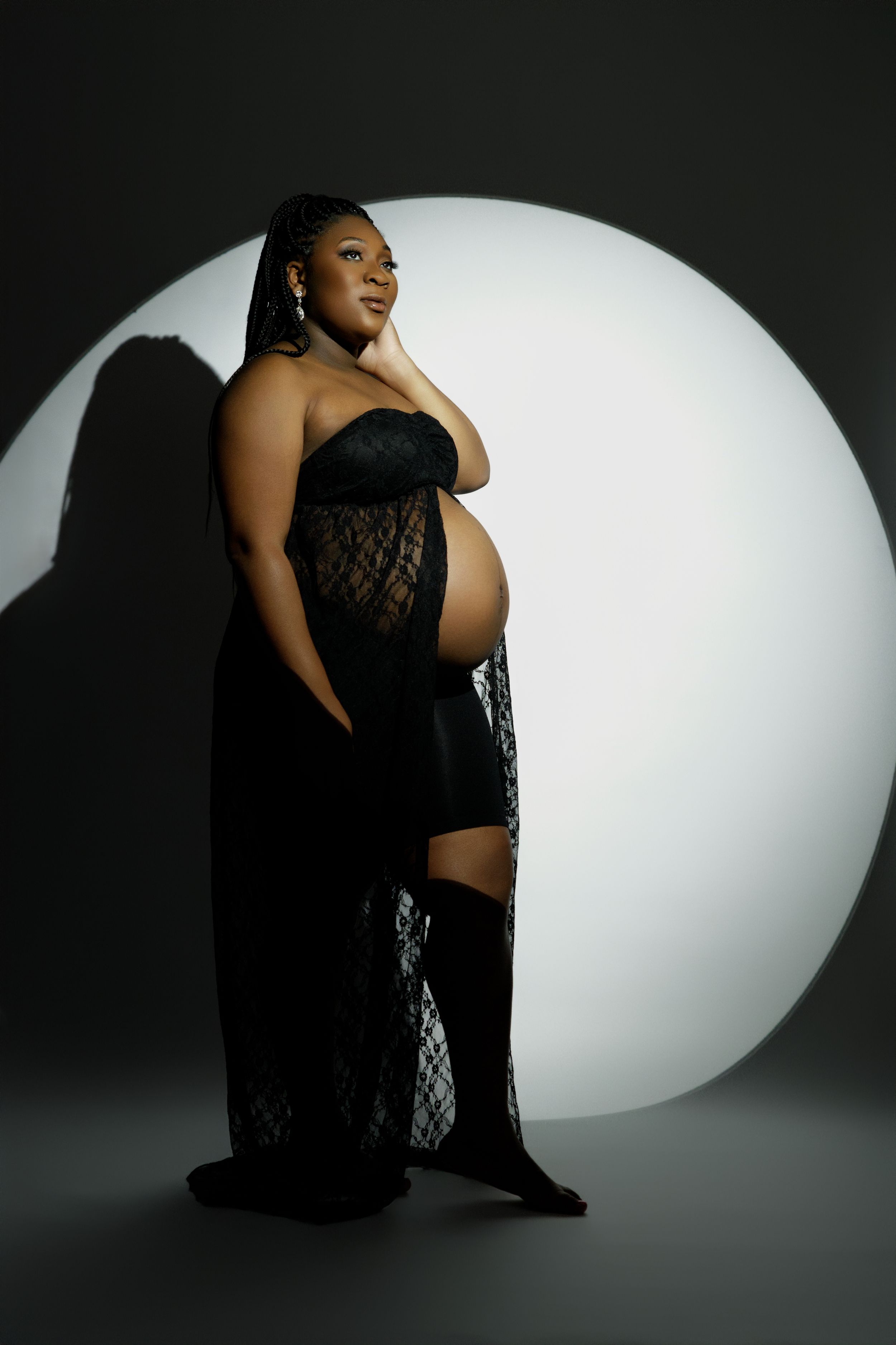Moody boudoir photoshoot with black lace fabric and dramatic oval lighting effect.