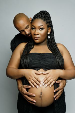 A series of intimate maternity photos showing a pregnant woman in black dress with hands embracing her belly.