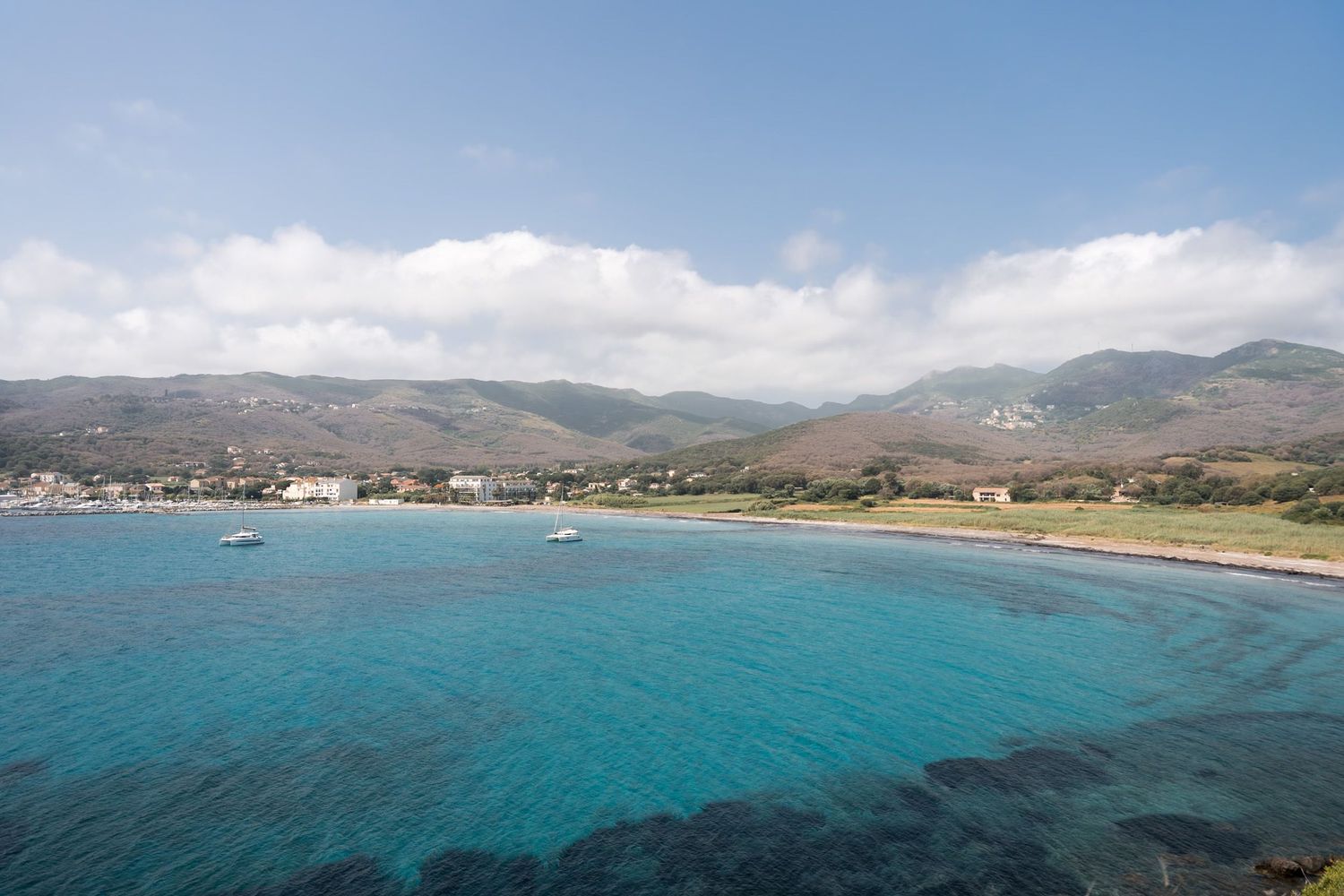baie de macinaggio avec la plage et les montagnes du cap corse en arrière plan