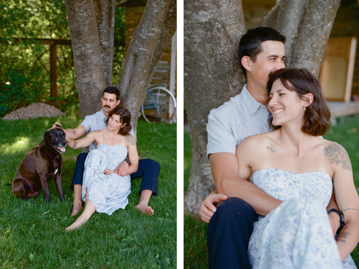 35 mm film photo of man and woman cuddling beside a tree, laughing and petting their brown lab dog