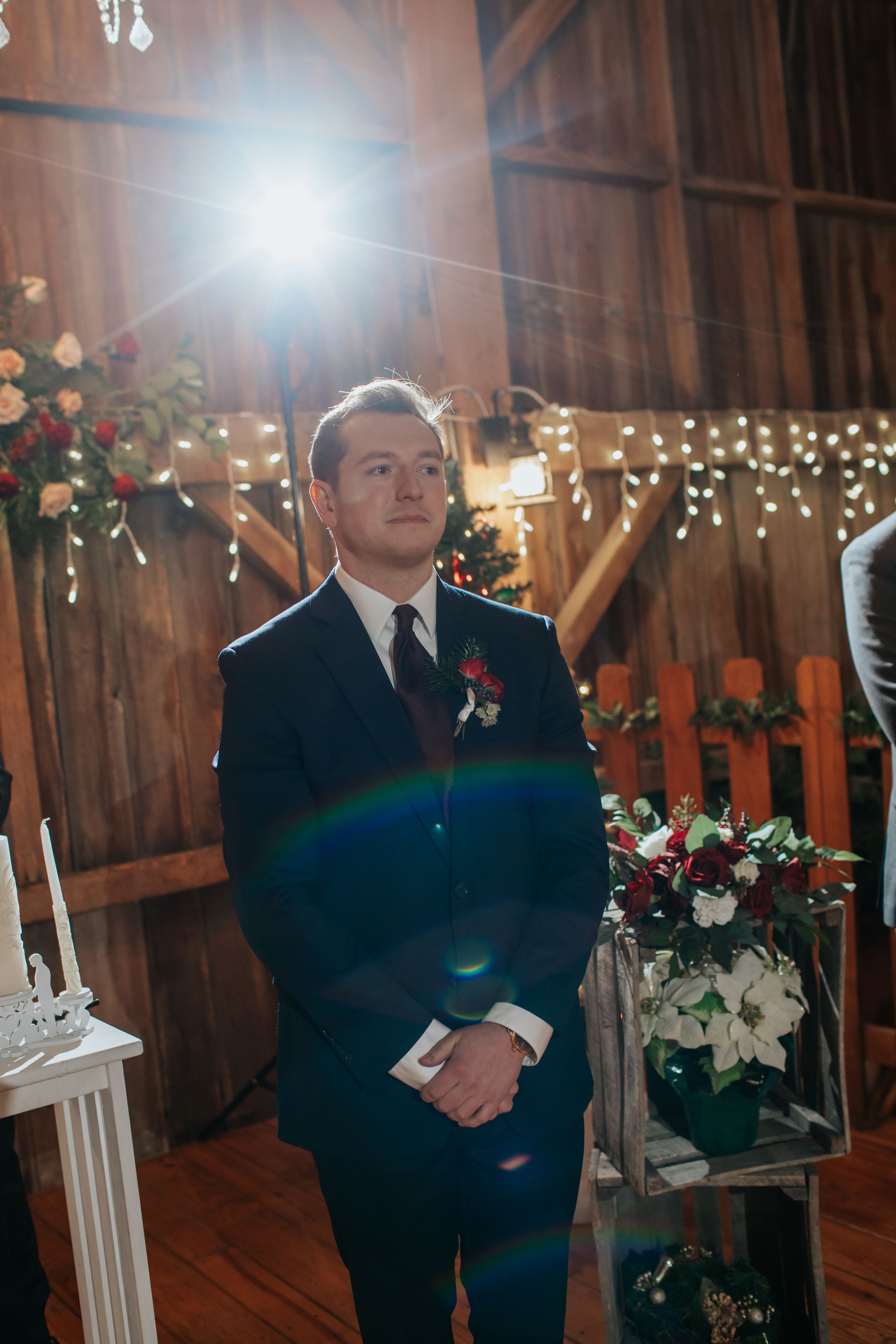A rustic barn wedding ceremony venue decorated with twinkling lights and floral arrangements.
