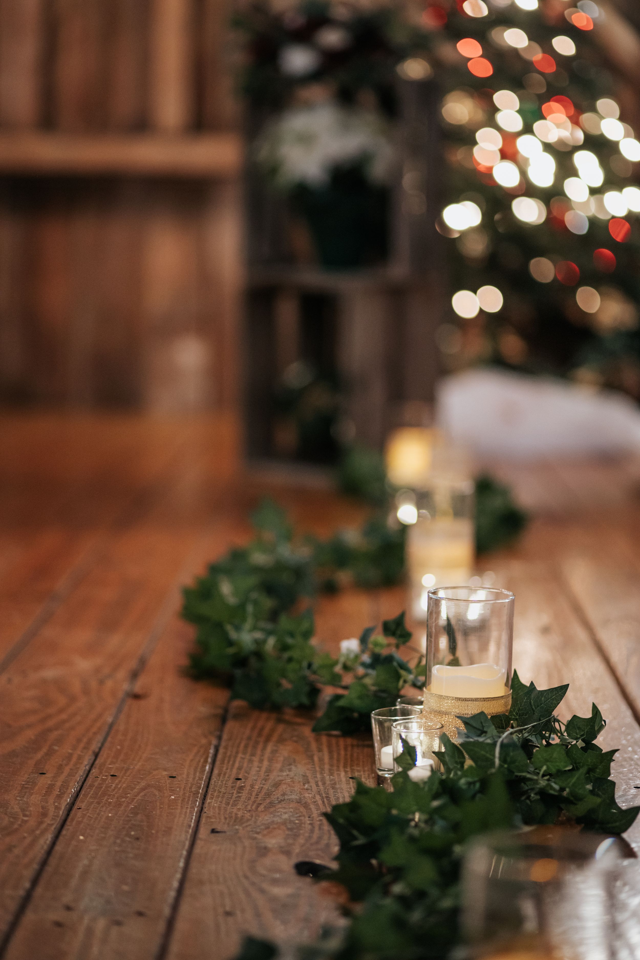 Rustic wooden table decorated with greenery garland and glowing candles creating romantic ambiance.