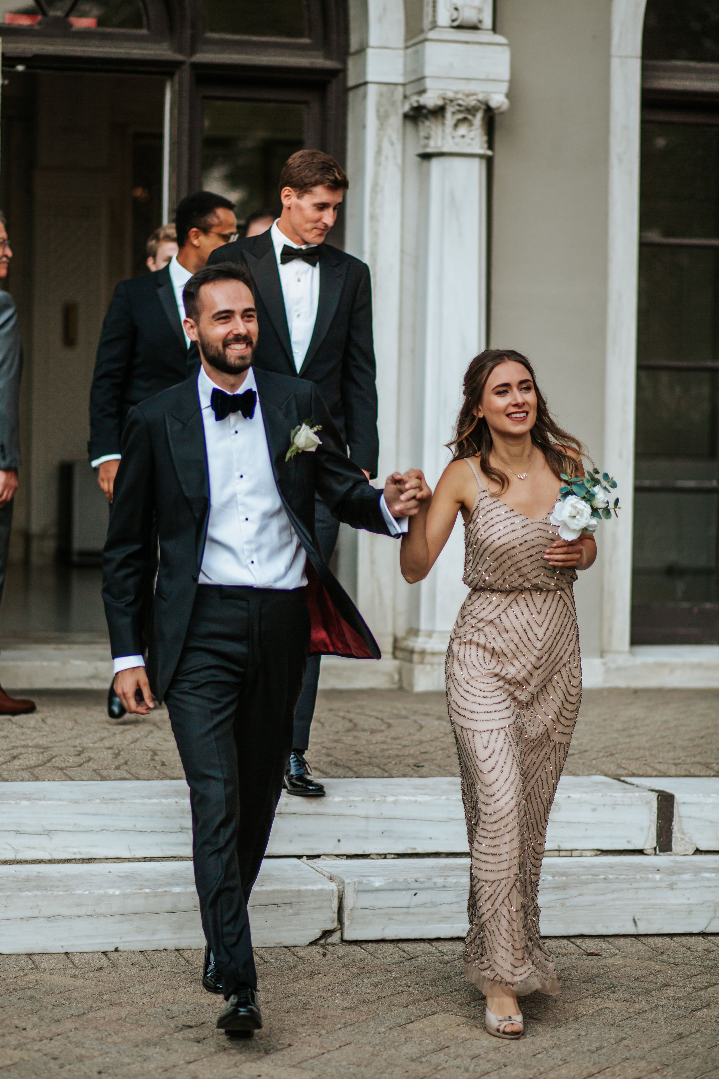 Wedding couple walks and laughs together during their celebration while wearing formal attire.