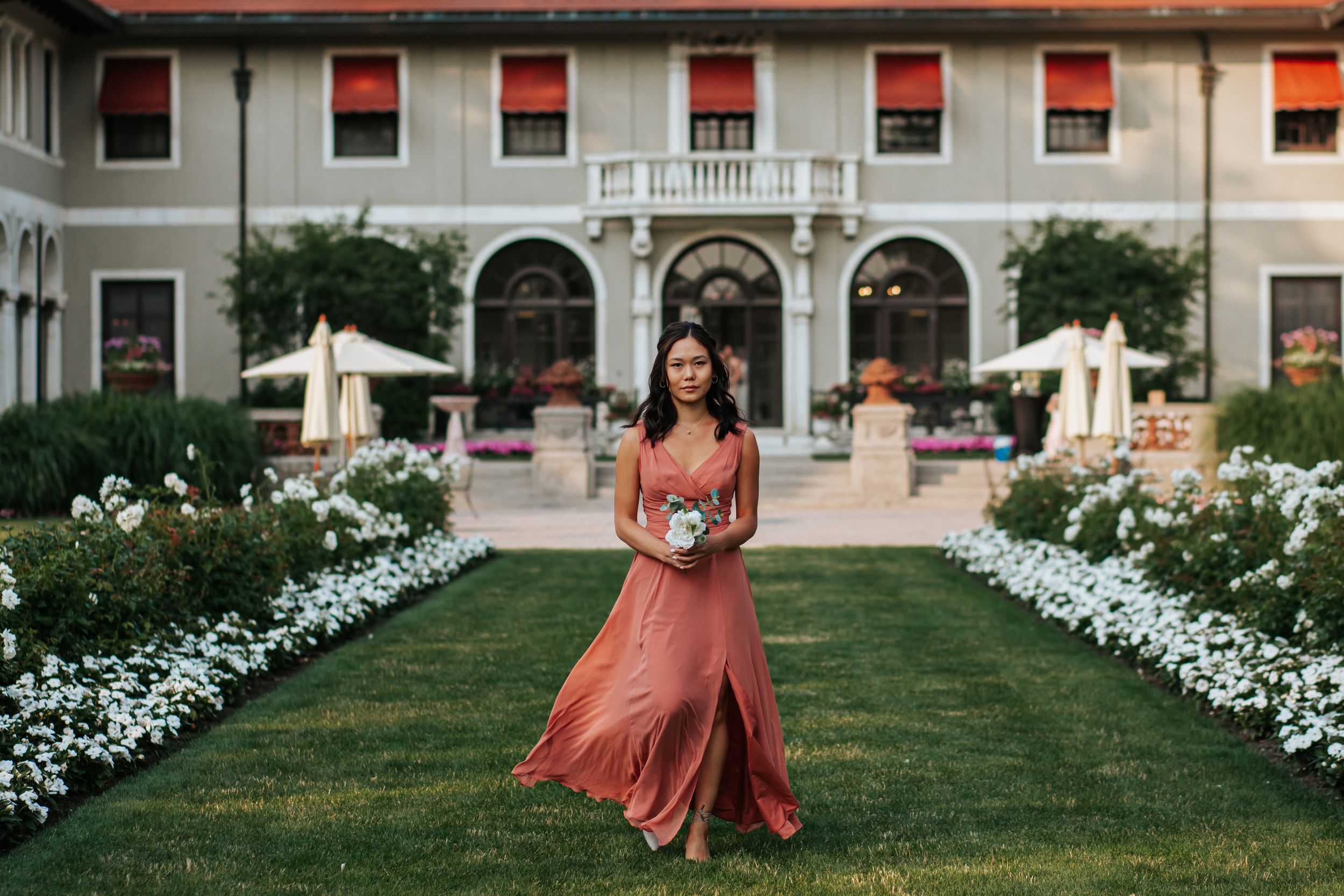 A series of wedding photos on a manicured lawn with white flowers and a Mediterranean-style building in the background.