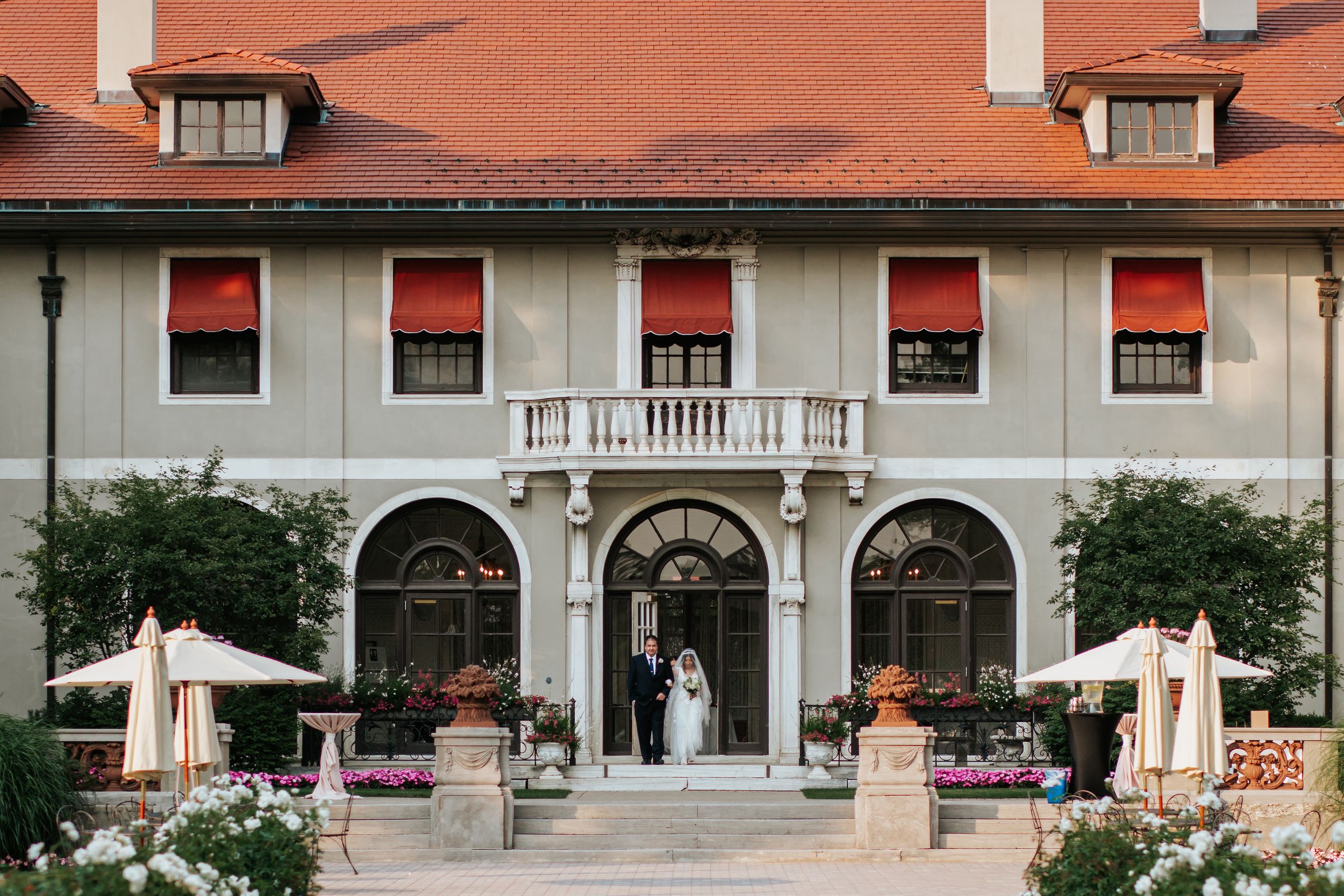 Elegant white mansion with red brick walls and colonial architecture features a grand entrance and covered porch area.
