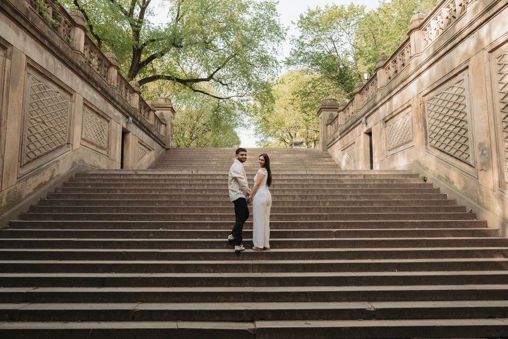 Couple standing together on grand stone staircase in urban setting.