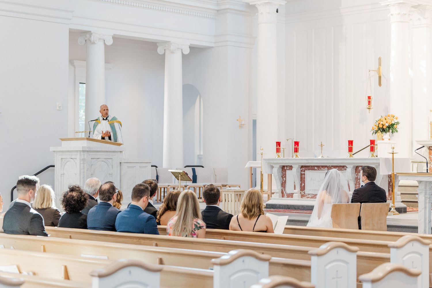 Interior view of a modern white church sanctuary with wooden pews and natural light streaming through windows.