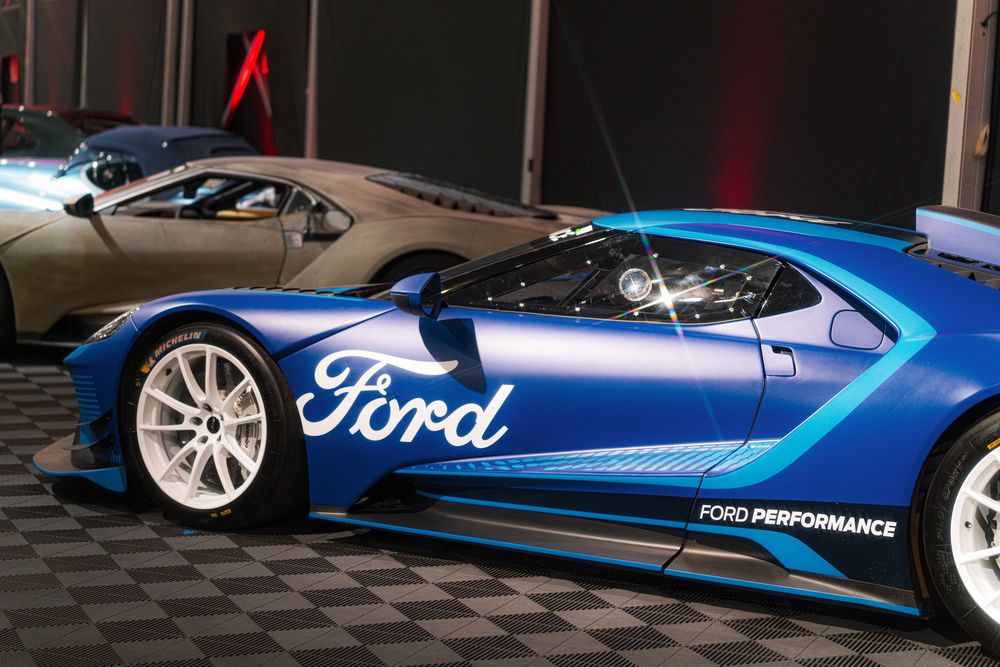 A sequence of blue Ford racing cars shown from different angles on display at an auto show.
