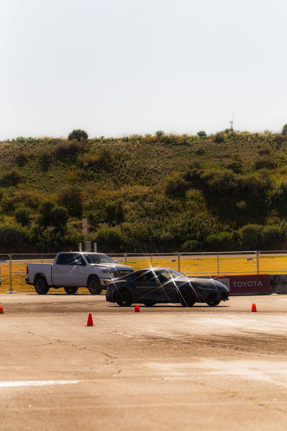 Multiple pickup trucks parked in a row at a dealership lot with orange traffic cones visible.