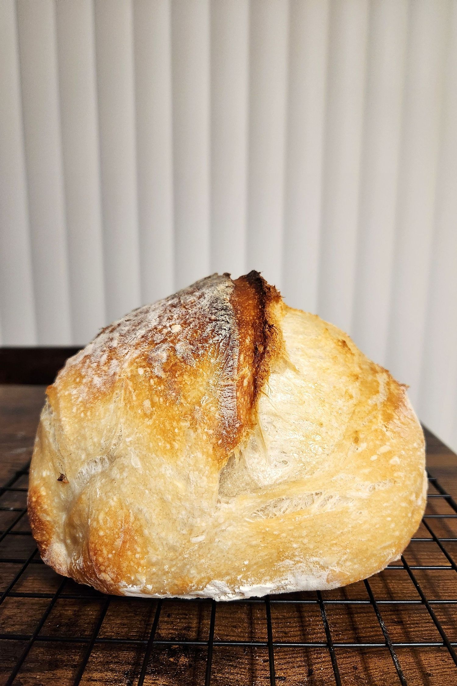 Fresh baked artisanal sourdough bread loaf with golden crust cooling on a wire rack.