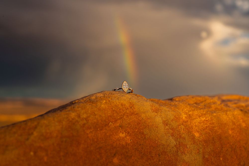 Stunning desert mountain landscape with golden light and rainbow at sunset.