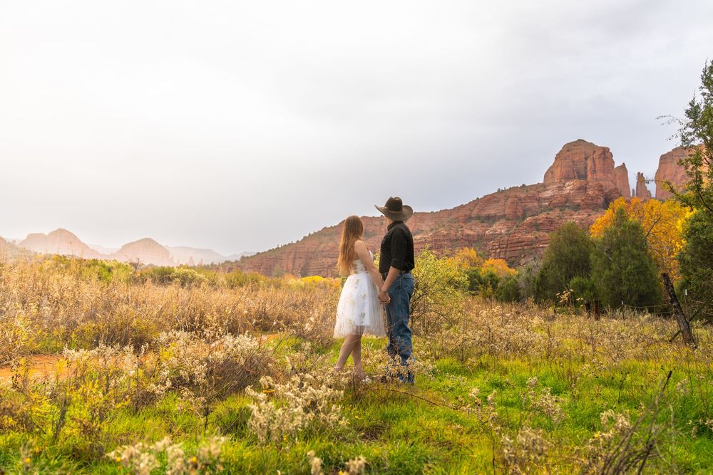 Scenic mountain landscape with red rock formations and desert vegetation in golden afternoon light.