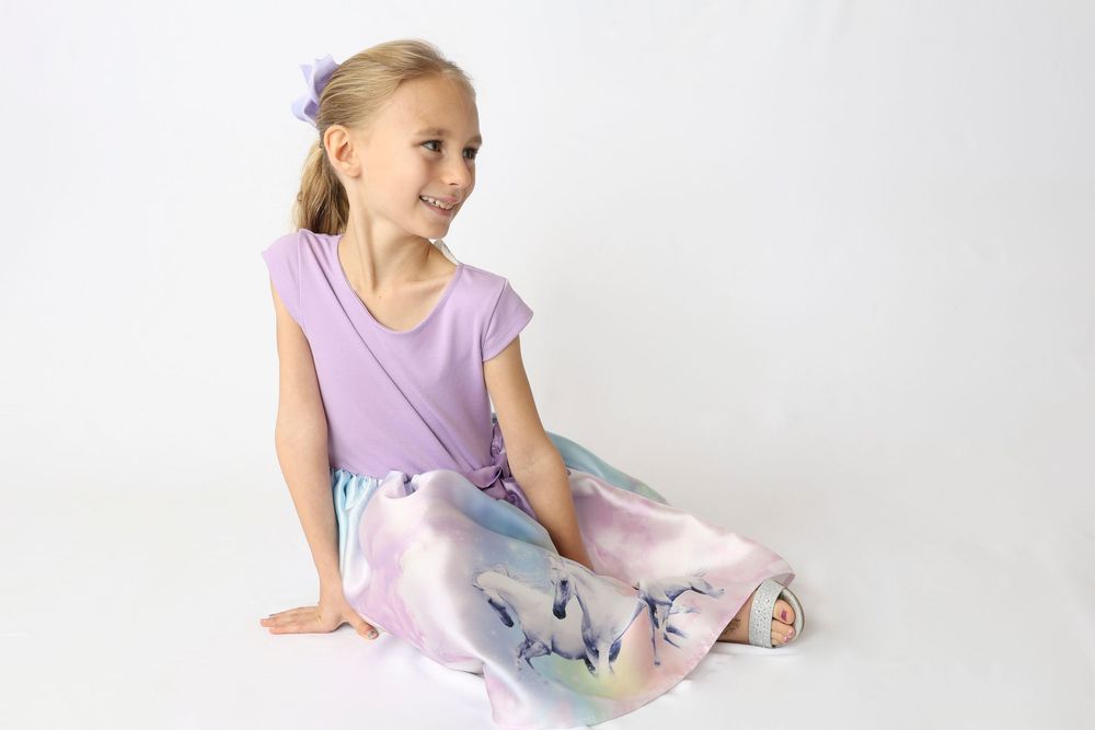 A person in a light purple leotard practices graceful ballet poses against a white studio backdrop.