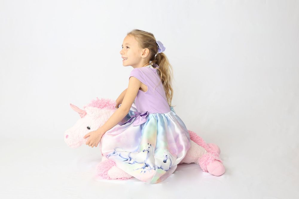 A child in a pastel dress performs graceful ballet poses against a white studio backdrop.