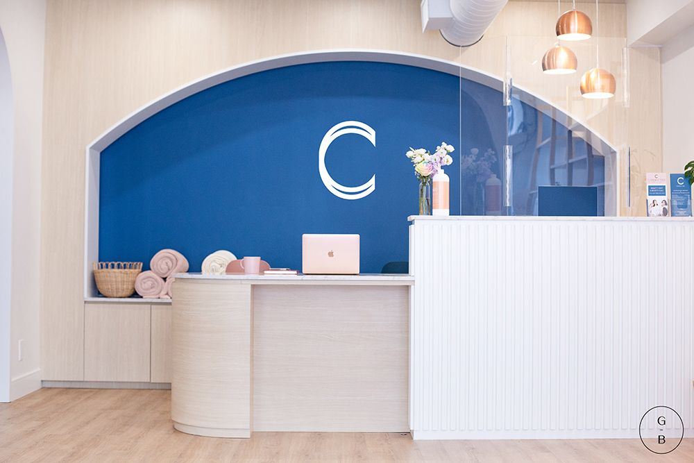 Modern office interior with white curved walls, blue accents, and pendant lighting creates a bright contemporary workspace.