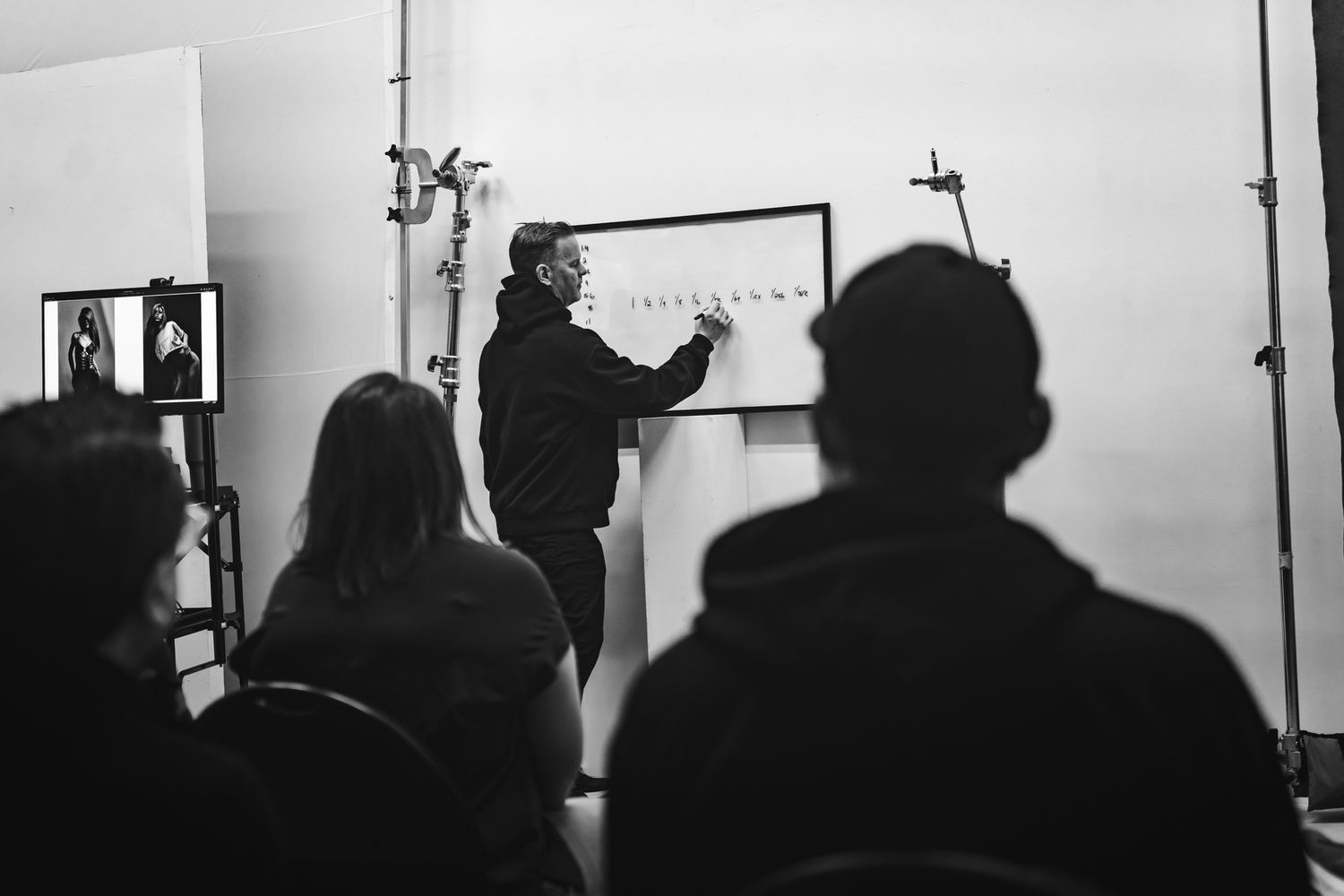 A black and white photo montage showing silhouettes of people in what appears to be a photography studio or gallery setting.