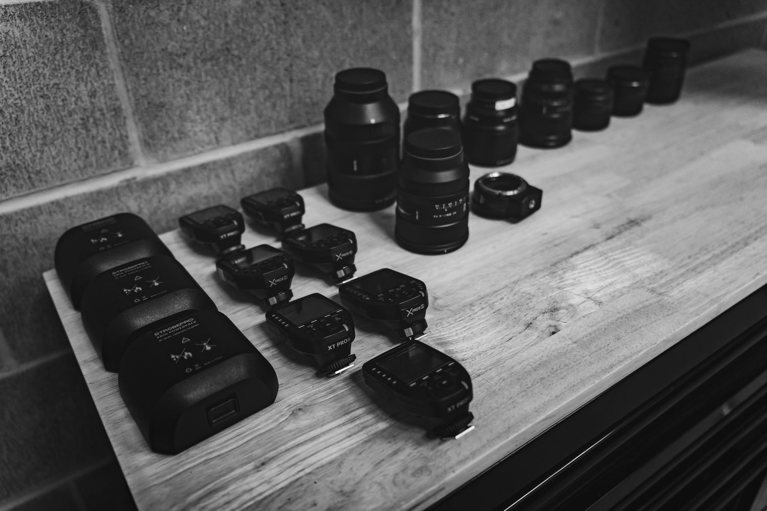 Black camera lenses arranged in a row on a wooden surface showing a collection of professional photography equipment.
