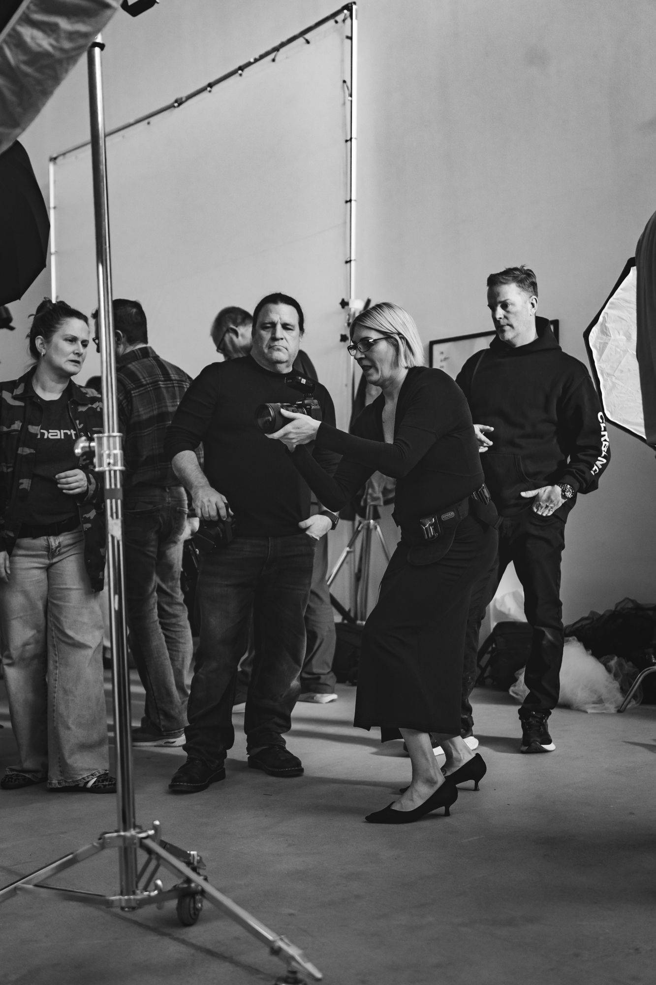 A black and white photo series showing people's feet and legs lined up against a wall during what appears to be a photoshoot.