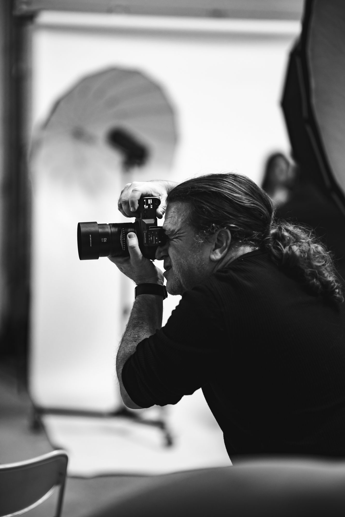 Silhouetted photographers using cameras in black and white, shown in a triptych composition.