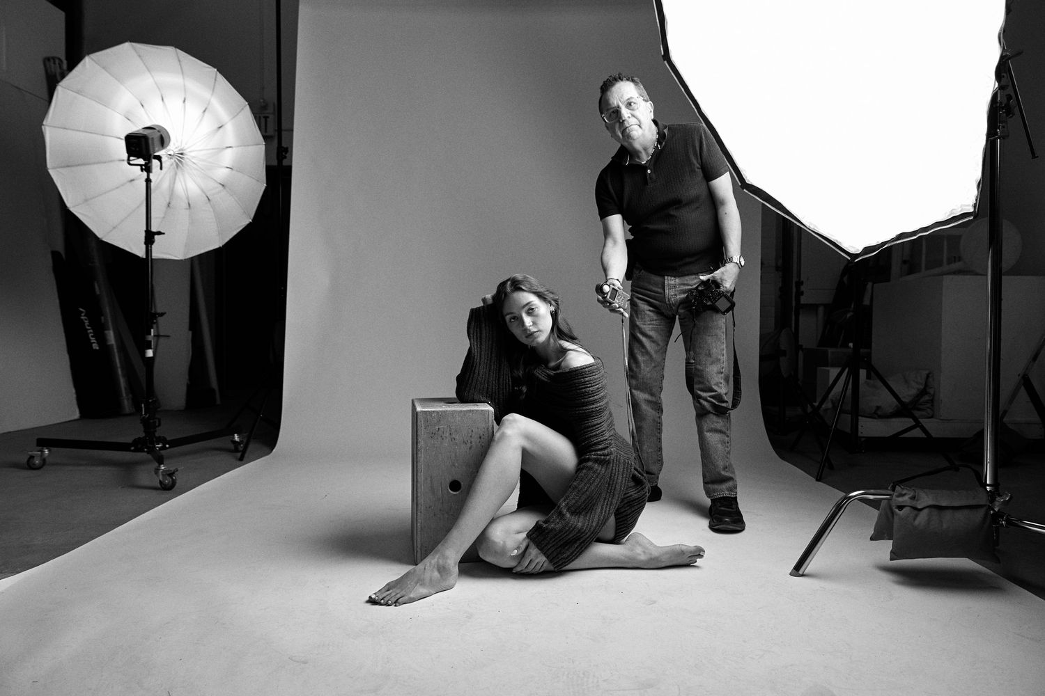Black and white photo of a photography studio setup with lighting equipment and two people during a professional shoot.