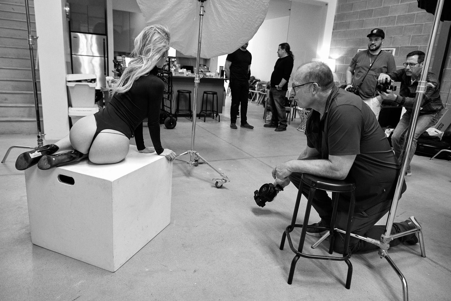 A series of connected black and white photos showing people working in a modern office space with white furniture.