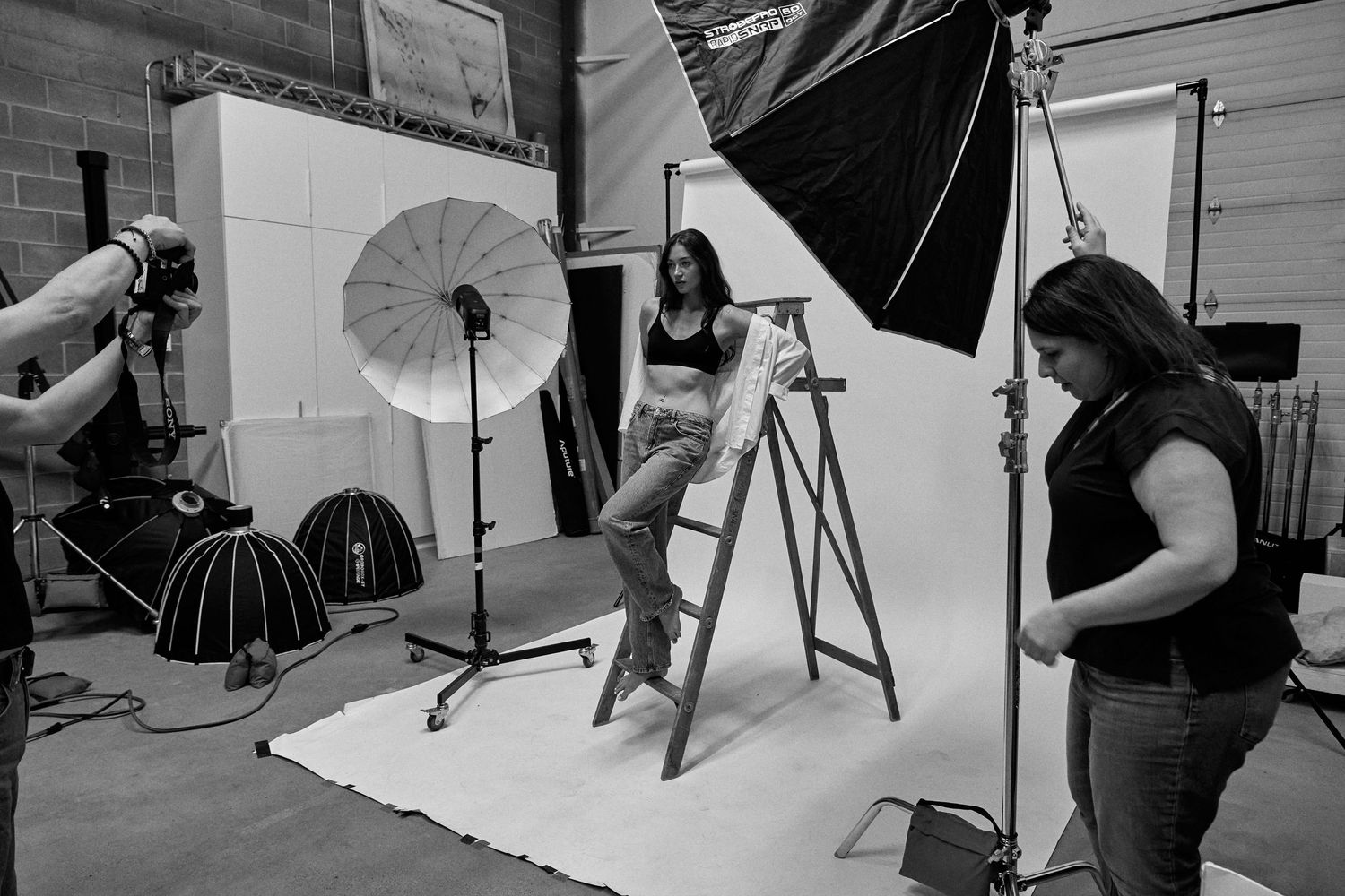 Professional photo studio setup showing lighting equipment, umbrellas, backdrops and camera gear arranged for portrait photography.