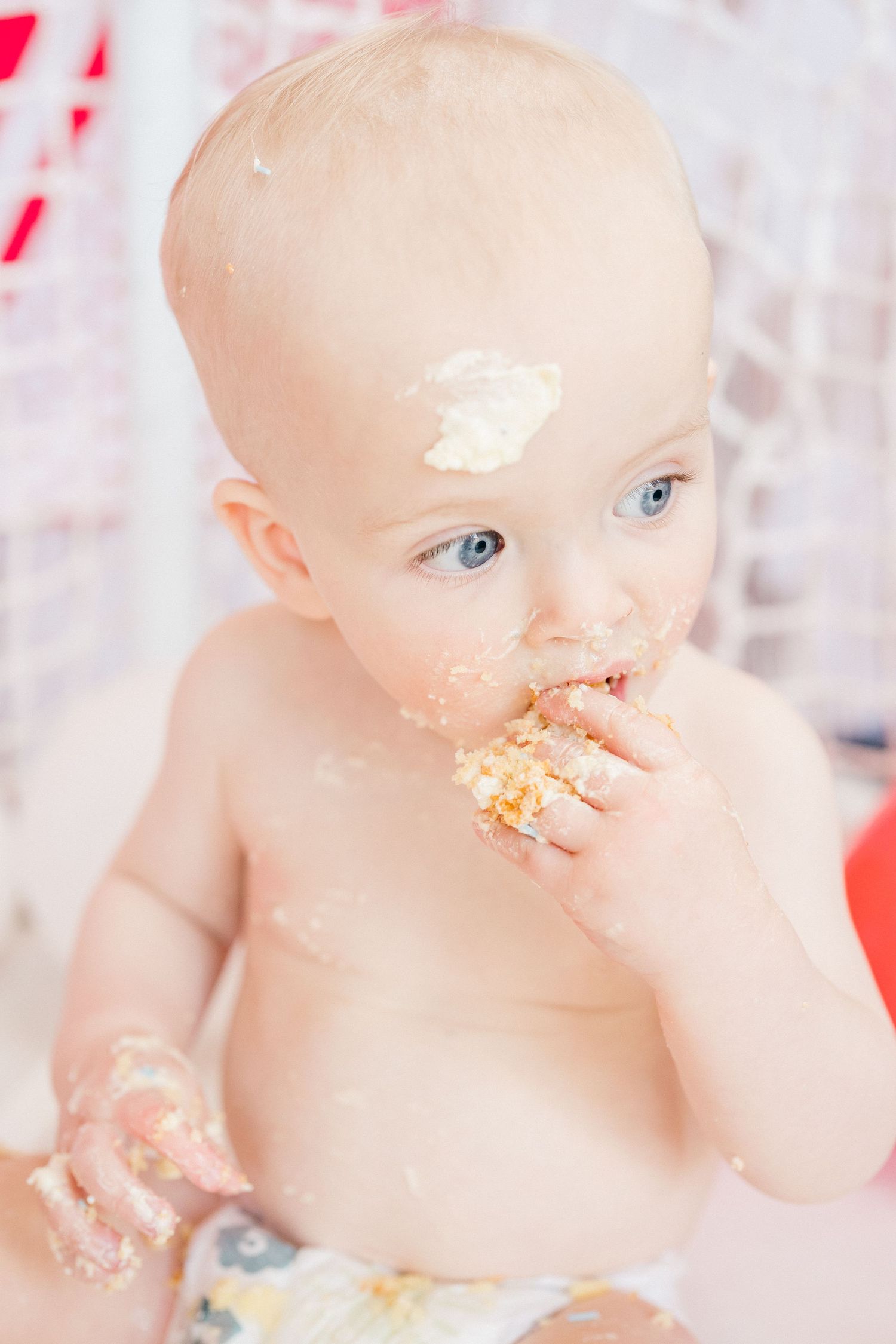 Documentary family photography of a baby eating birthday cake, captured naturally during an unposed family photoshoot