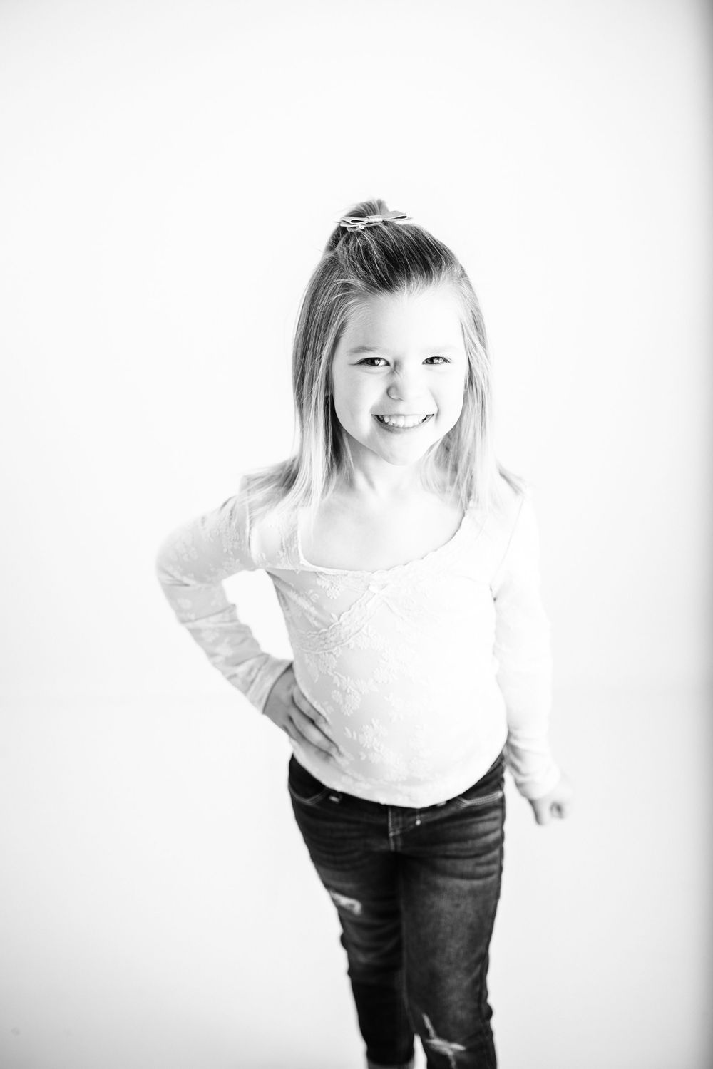 A child in jeans and white shirt poses playfully against a white background in a series of candid shots.