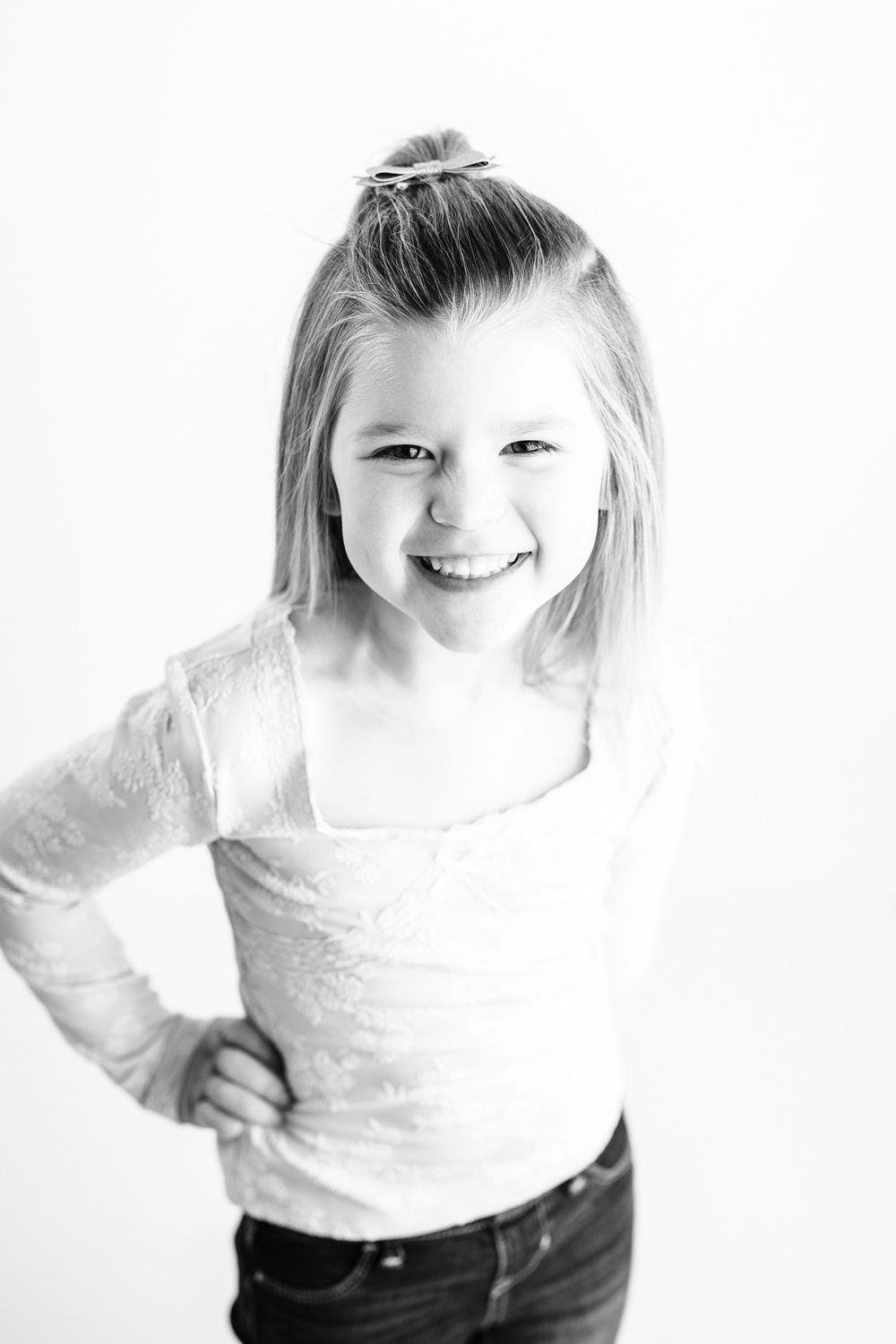 A series of three black and white photos showing a joyful child wearing a white top and dark pants.
